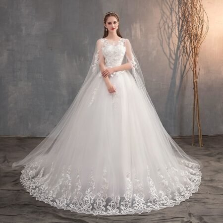 An elegant wedding gown with a long train embroidered with princess embroidery features a long cape and long train.